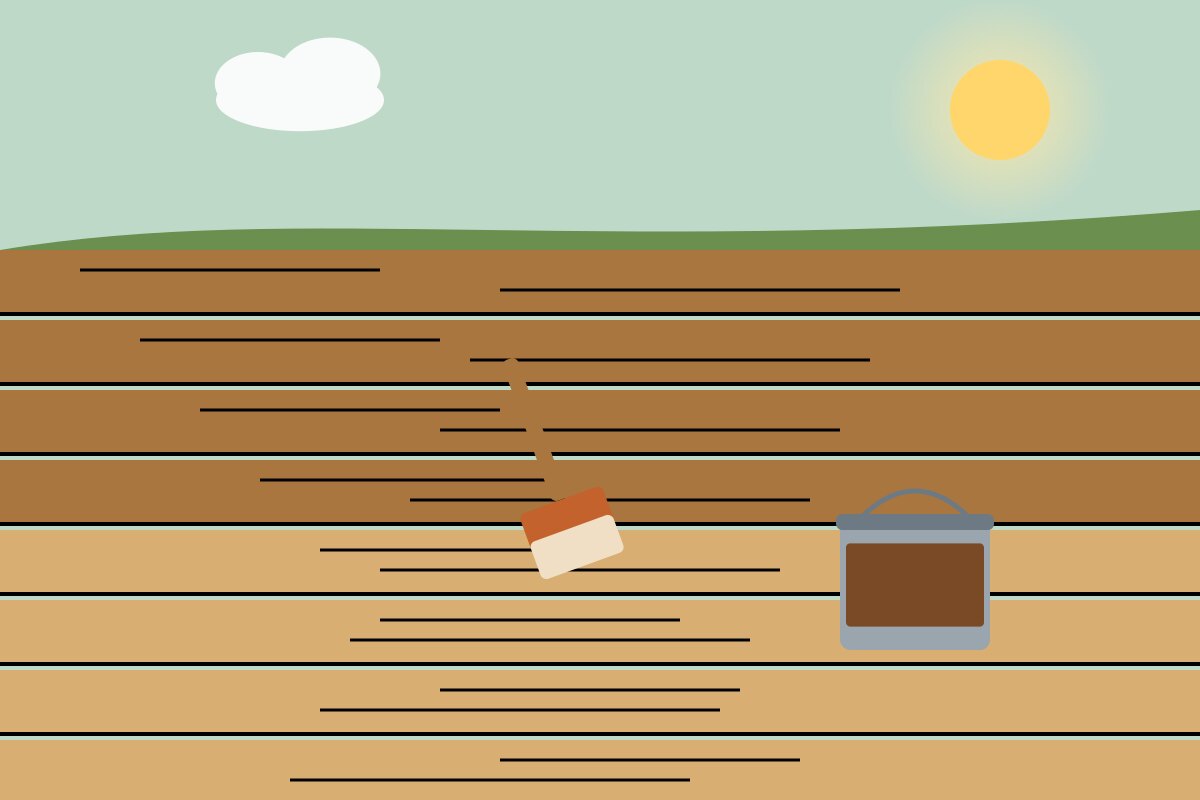 A wooden deck half stained with a brush and a can